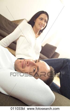 Stock Image - Young couple relaxing on the floor in their living room. Fotosearch