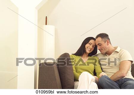 Young couple sitting on sofa View Large Photo Image Stock Image - Young couple sitting on sofa. Fotosearch