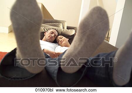 Young couple sleeping on sofa with their feet up View Large Photo Image Stock Image - Young couple sleeping on sofa with their feet up. Fotosearch