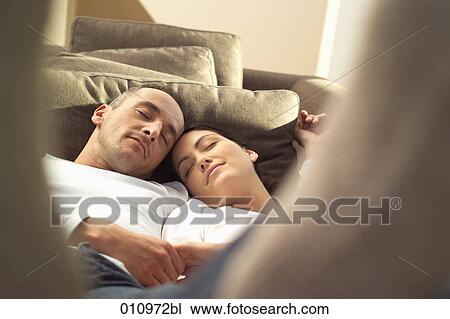 Stock Image - Young couple sleeping together on sofa. Fotosearch