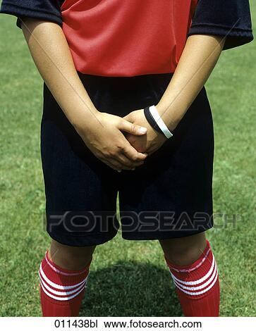 Stock Image - young football player holding his hands before his soft parts. Fotosearch