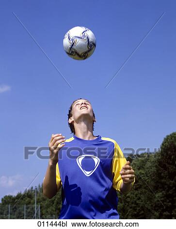 Stock Image - young footballer doing headers during football training. Fotosearch