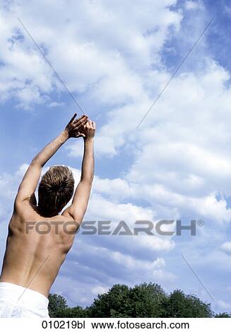 Stock Image - young man (20-25 years) doing wellness training in the park. Fotosearch