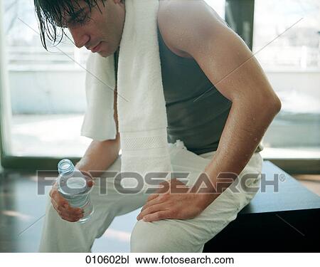 Stock Image - young man after workout holding a bottle of water. Fotosearch
