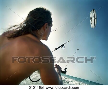Stock Image - young man flying kite on the beach. Fotosearch
