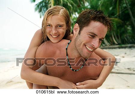 young man giving his girlfriend a piggyback ride on the beach View Large Photo Image Stock Image - young man giving his girlfriend a piggyback ride on the beach. Fotosearch