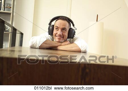 Young man listening to music on headphones View Large Photo Image Stock Image - Young man listening to music on headphones. Fotosearch