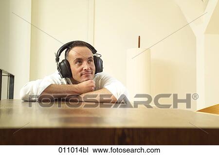 Young man listening to music with thoughtful expression View Large Photo Image Stock Image - Young man listening to music with thoughtful expression. Fotosearch