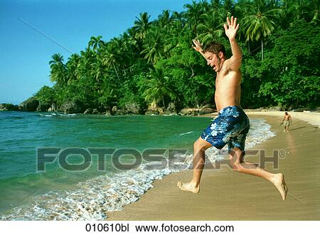 young man on tropical beach jumping into the surf View Large Photo Image Stock Image - young man on tropical beach jumping into the surf. Fotosearch