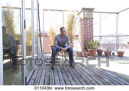 Young man sitting alone on a terrace View Large Photo Image Stock Image - Young man sitting alone on a terrace. Fotosearch