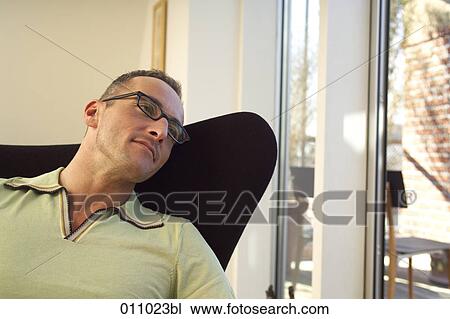 Young man sitting in chair looking out of window View Large Photo Image Stock Image - Young man sitting in chair looking out of window. Fotosearch
