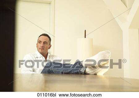 Young man with feet on the table View Large Photo Image Stock Image - Young man with feet on the table. Fotosearch