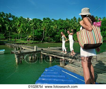 Stock Image - young tourists arriving at tropical island. Fotosearch