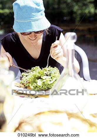 Stock Image - young woman (20-25 years) eating salad for lunch . Fotosearch