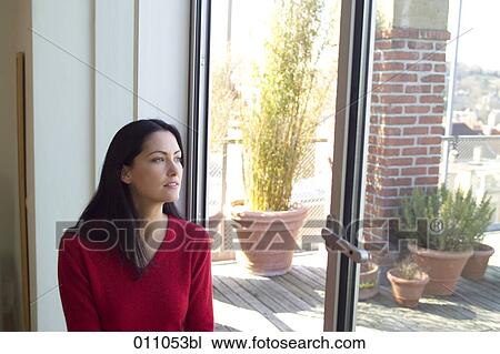 Young woman looking through window on terrace View Large Photo Image Stock Image - Young woman looking through window on terrace. Fotosearch