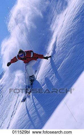 Stock Image - young woman racing down mountain on skis. Fotosearch