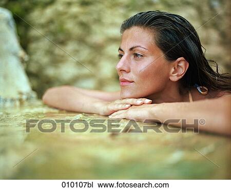Stock Image - young woman relaxing in a natural pool. Fotosearch