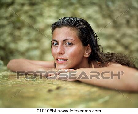 Stock Image - young woman relaxing in a natural pool. Fotosearch