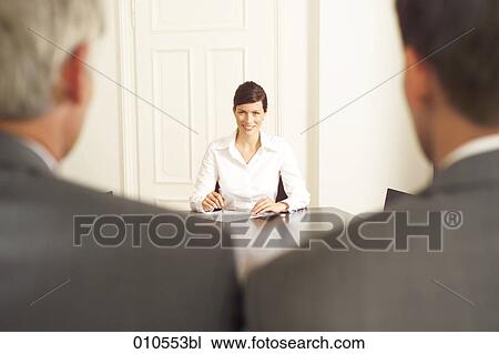young woman sitting at a conference table with two businessmen in the foreground View Large Photo Image Stock Image - young woman sitting at a conference table with two businessmen in the foreground. Fotosearch