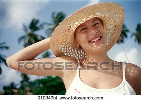 Stock Image - young woman with large summer straw hat. Fotosearch