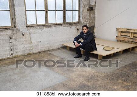 businessman sitting on wooden pallet in empty building View Large Photo Image Stock Image - businessman sitting on wooden pallet in empty building. Fotosearch