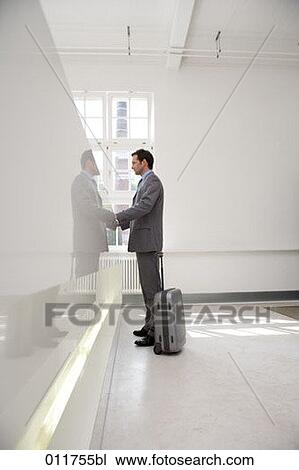 Stock Image - businessman with silver suitcase beside him waiting at reception. Fotosearch