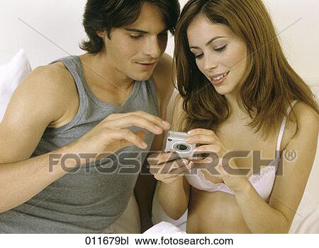 Stock Image - close-up of young couple checking pictures on digital camera. Fotosearch
