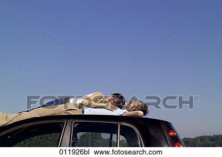 couple dozing on the top of their car View Large Photo Image Stock Image - couple dozing on the top of their car. Fotosearch