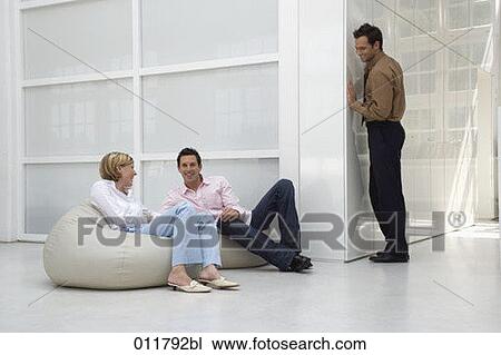 Stock Image - group of three friends having fun in an office building. Fotosearch