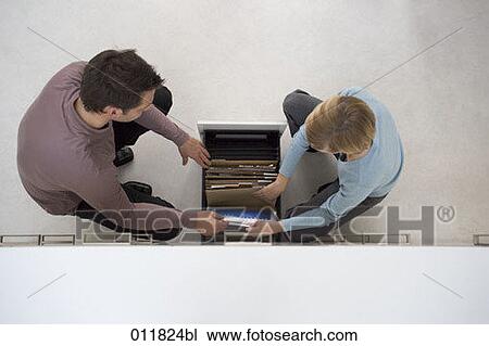 high angle view of two office workers thumbing through filing cabinet drawer View Large Photo Image Stock Image - high angle view of two office workers thumbing through filing cabinet drawer. Fotosearch