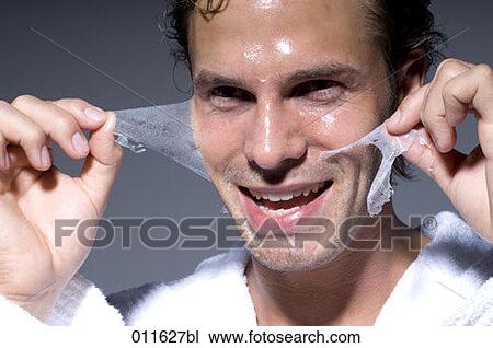 Stock Image - man peeling off his face mask. Fotosearch
