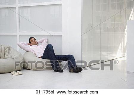 Stock Image - man sitting comfortalby on bean bag. Fotosearch