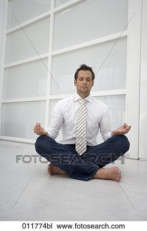 Stock Image - man sitting in office environment meditating . Fotosearch