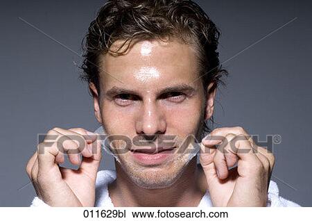 Stock Image - portrait of man peeling off his face mask. Fotosearch