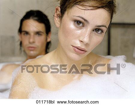 Stock Image - portrait of serious looking young woman in bubble bath. Fotosearch