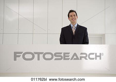Stock Image - portrait of smiling receptionist behind desk. Fotosearch