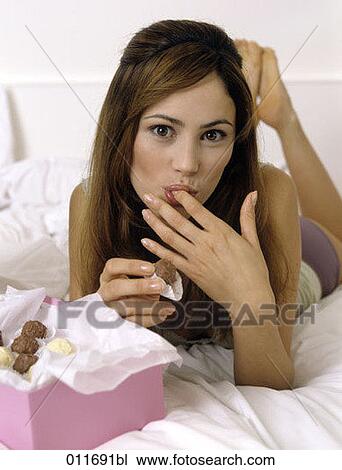 Stock Image - portrait of young woman enjoying chocolates. Fotosearch