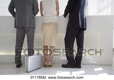 rear view of three business people standing at reception desk View Large Photo Image Stock Image - rear view of three business people standing at reception desk. Fotosearch