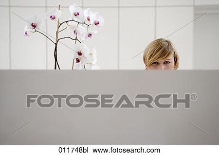 Stock Image - receptionist sitting behind desk in office building. Fotosearch