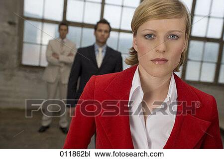 serious looking woman standing in front of two businessmen in empty factory building View Large Photo Image Stock Image - serious looking woman standing in front of two businessmen in empty factory building. Fotosearch