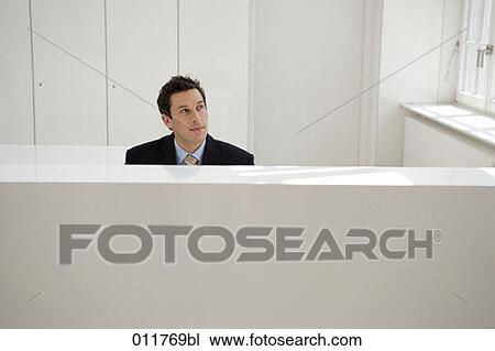 thoughtful looking man sitting at reception in office building View Large Photo Image Stock Image - thoughtful looking man sitting at reception in office building. Fotosearch