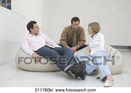 Stock Image - three people relaxing on bean bags and talking. Fotosearch
