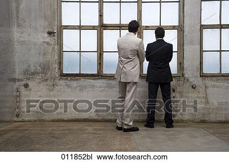 two businessmen looking out of window in empty building View Large Photo Image Stock Image - two businessmen looking out of window in empty building. Fotosearch
