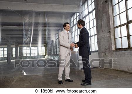 two businessmen shaking hands in empty factory building View Large Photo Image Stock Image - two businessmen shaking hands in empty factory building. Fotosearch