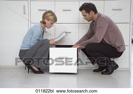 two casually dressed office workers checking file at filing cabinet View Large Photo Image Stock Image - two casually dressed office workers checking file at filing cabinet. Fotosearch