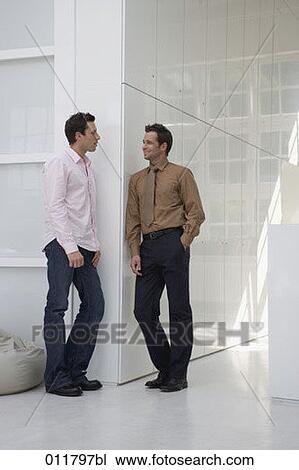 Stock Image - two men standing in office building and having a conversation. Fotosearch