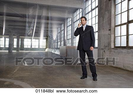 young businessman using his cellphone in empty factory building View Large Photo Image Stock Image - young businessman using his cellphone in empty factory building. Fotosearch