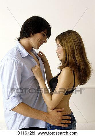 Stock Image - young couple face to face, woman unbottoning shirt of man. Fotosearch