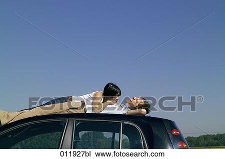 young couple sharing a laugh on car top View Large Photo Image Stock Image - young couple sharing a laugh on car top. Fotosearch