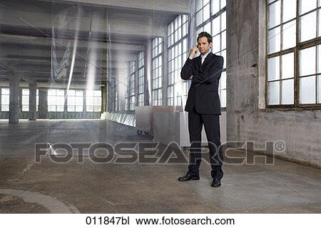 young estate agent standing in empty building and talking on his cellphone View Large Photo Image Stock Image - young estate agent standing in empty building and talking on his cellphone. Fotosearch